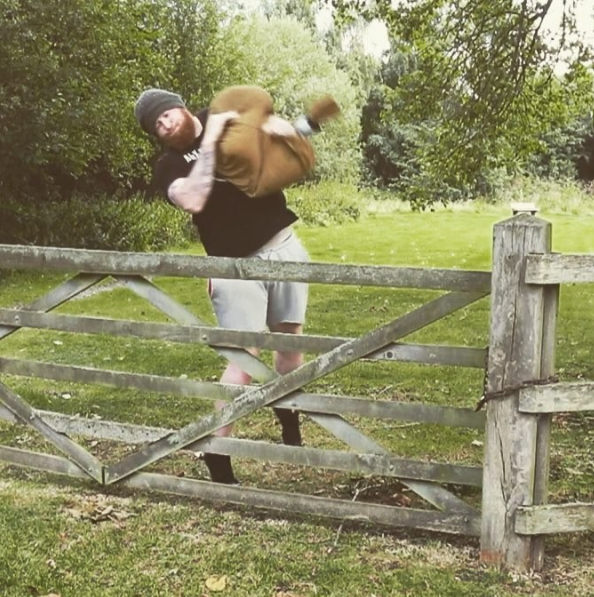 Phil Bennett of Complete MMA hoisting a sandbag over a fence