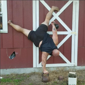 Bud Jeffries doing a one arm handstand on a kettlebell